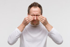 man rubbing both of his eyes