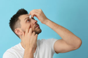 man applying eye drops