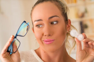 woman holding contact lenses and eyeglasses